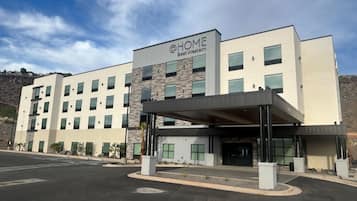 A multi-story hotel with a modern facade, a covered entrance, and a parking lot.