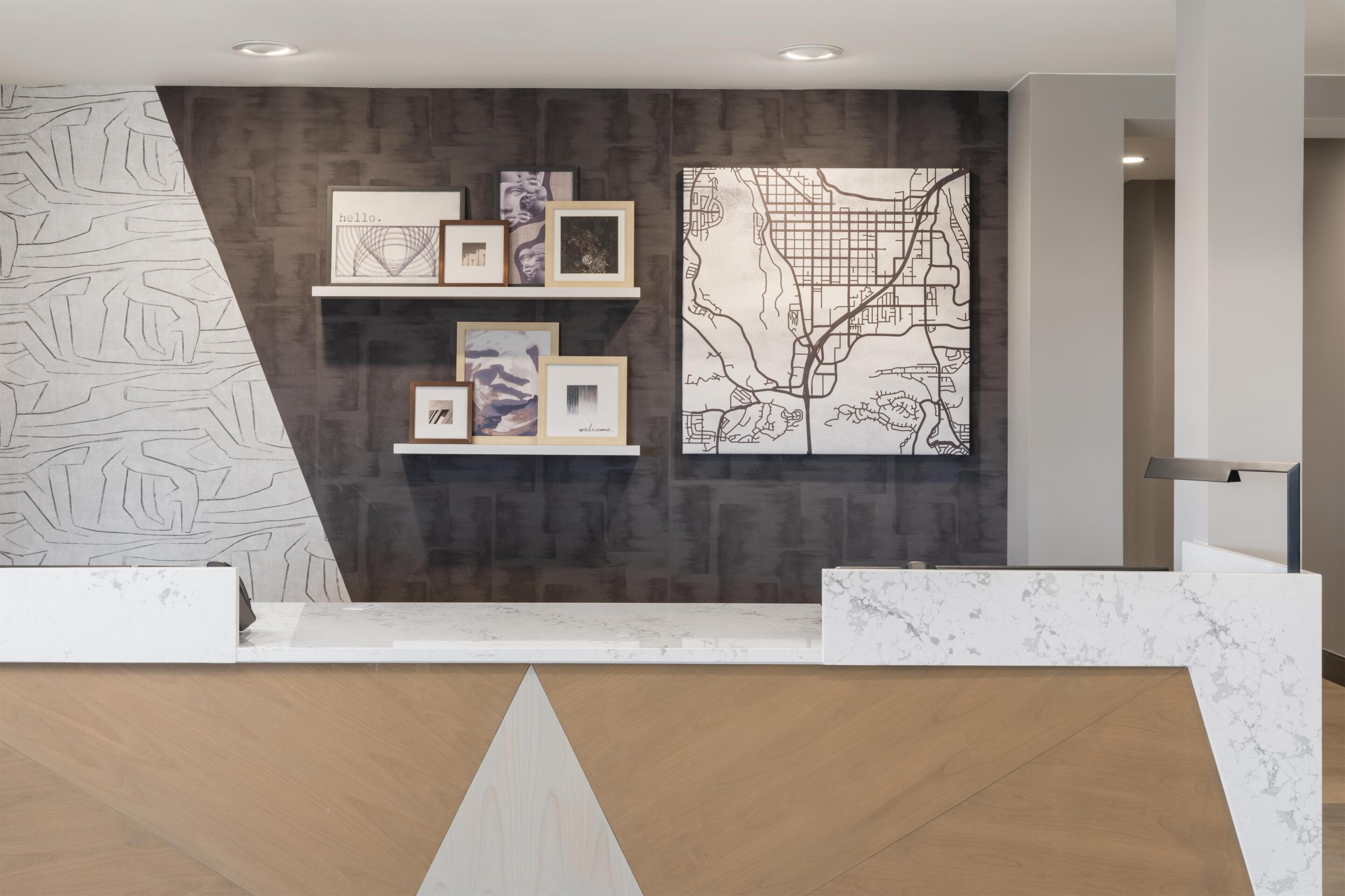A reception area with a marble counter, framed artwork on shelves, and a large map on the wall.
