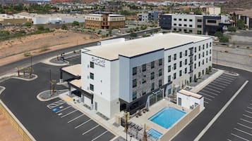 Un hotel moderno con piscina, estacionamiento y vistas del entorno.