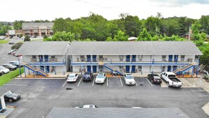 A motel with a parking lot, multiple floors, and a staircase leading to the entrance. - Travelers Inn and Suites (Paducah)