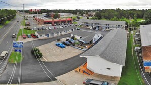 A motel with a parking lot, a Travelers Inn & Suites sign, and a visible gas station in the background. - Travelers Inn and Suites (Paducah)