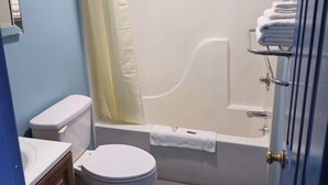 A bathroom with a toilet, bathtub, and shower curtain. - Travelers Inn and Suites (Paducah)