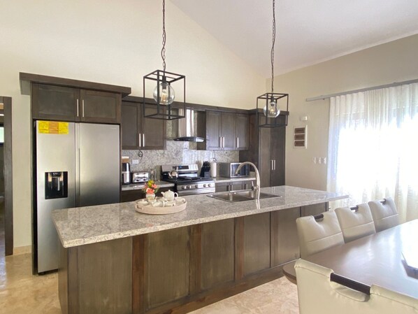 A modern kitchen with dark wood cabinets, stainless steel appliances, and a granite countertop.