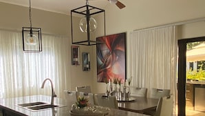 Una cocina moderna con una isla central, un comedor con mesa y sillas, y un ventilador de techo.