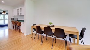 A modern kitchen with white cabinets, a wooden dining table, and black chairs.