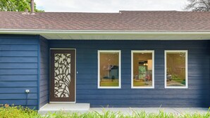 A house with a dark blue exterior, a decorative door, and three windows.
