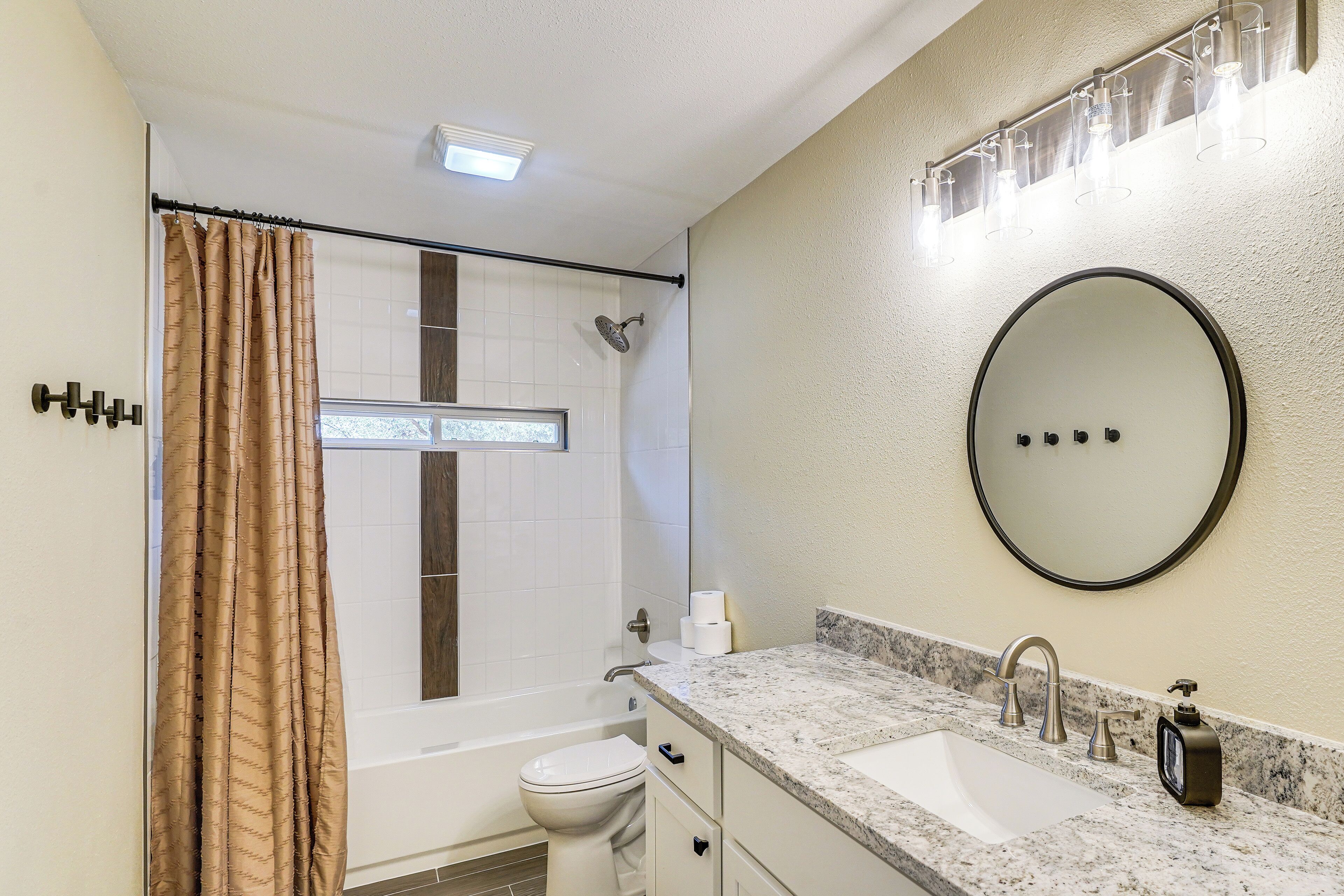 A bathroom with a shower, toilet, sink, and mirror.