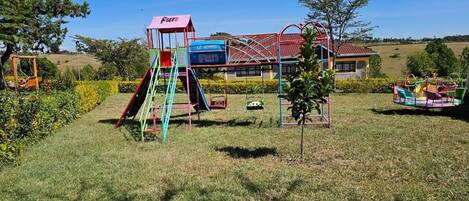 Une aire de jeux avec un toboggan, une structure d’escalade et des balançoires.