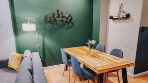 A modern living room with a wooden dining table, grey sofa, and blue chairs. - Convention / 3 King Beds / Jet Shower / 65" TV (Philadelphia)