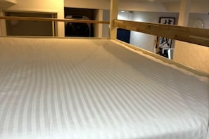 A room with a bed, wooden headboard, and a door leading to another room. - Airandohausu (Tokyo)
