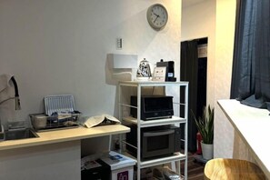 A room with a desk, shelves, a clock, a plant, and a window. - Airandohausu (Tokyo)