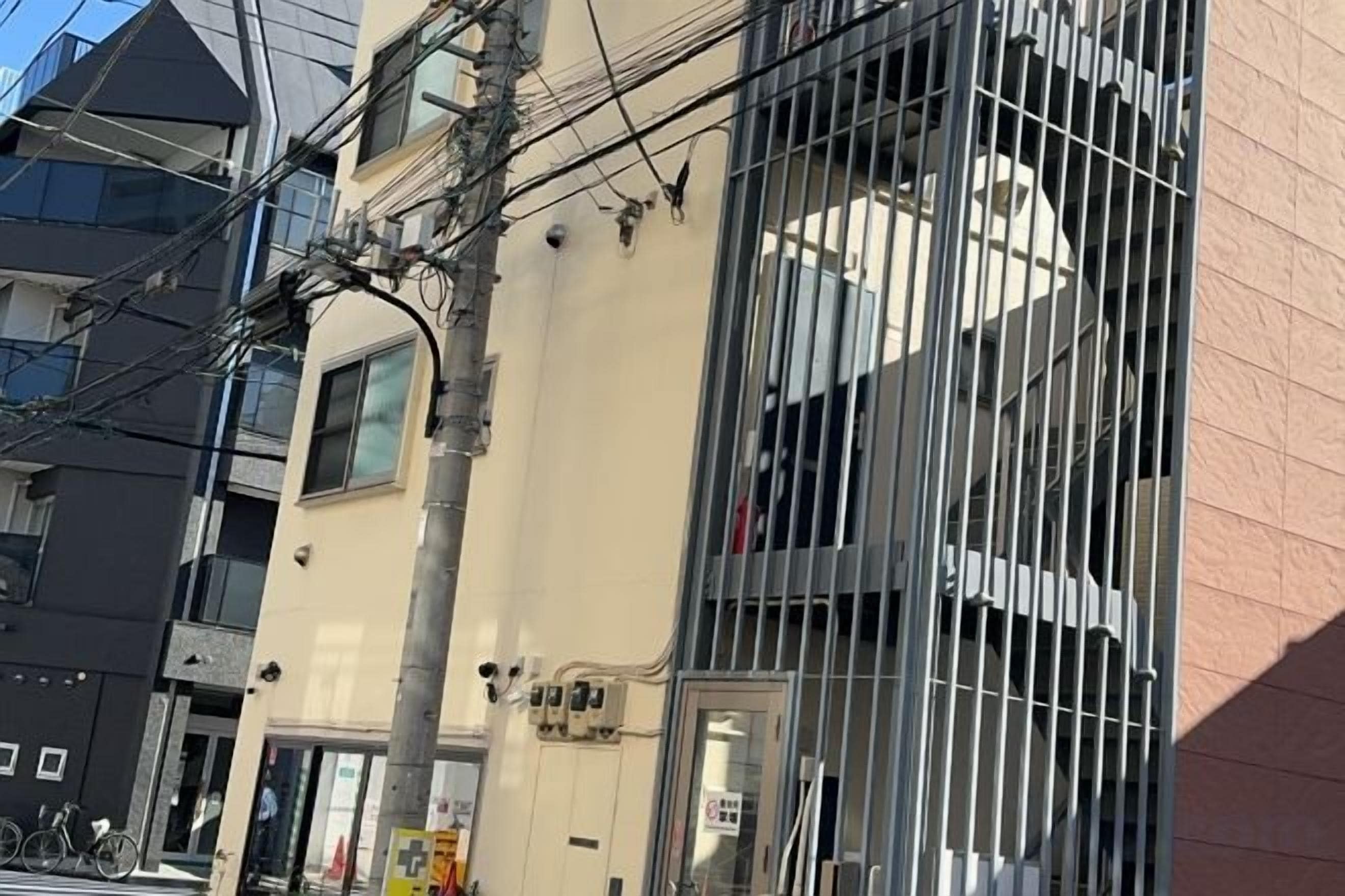 A multi-story building with barred windows and visible electrical wiring.