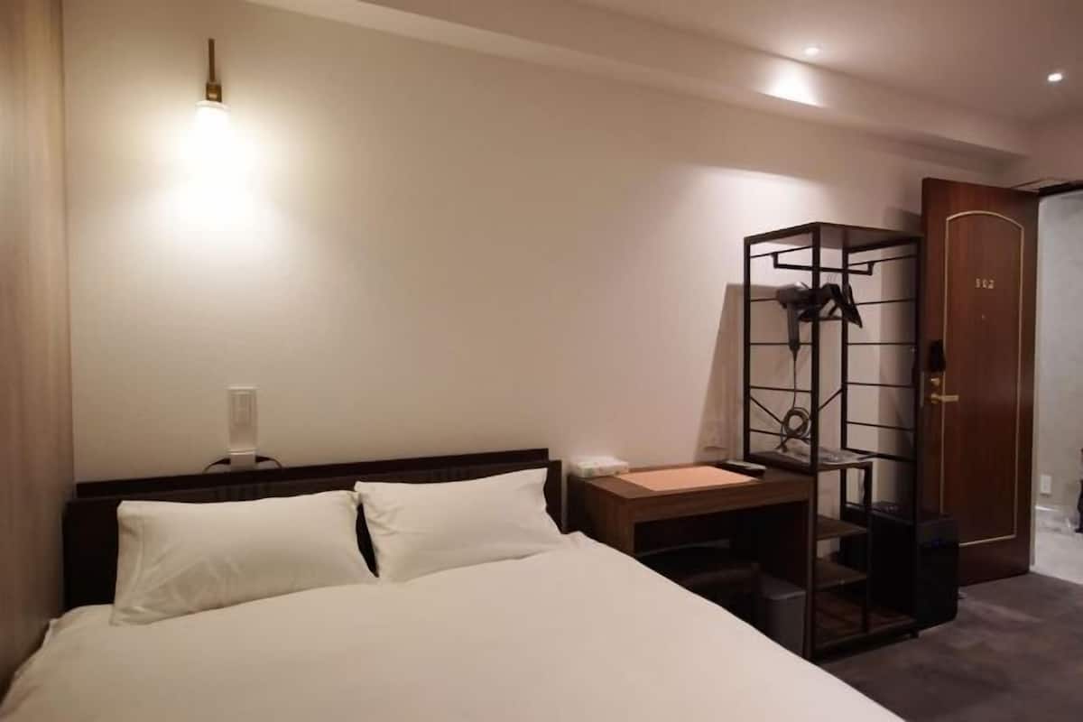 A hotel room with a bed, bedside table, and a wardrobe.