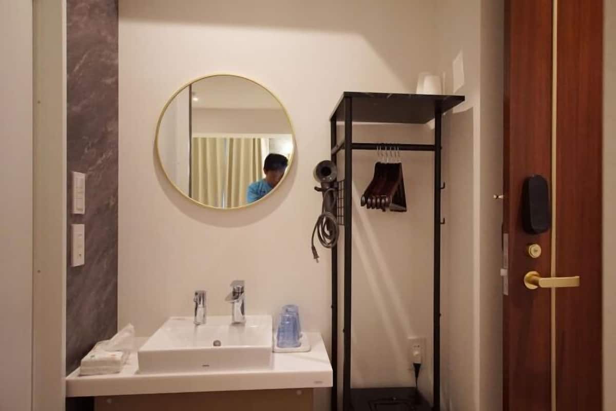 A bathroom with a white sink, a round mirror, and a towel rack.