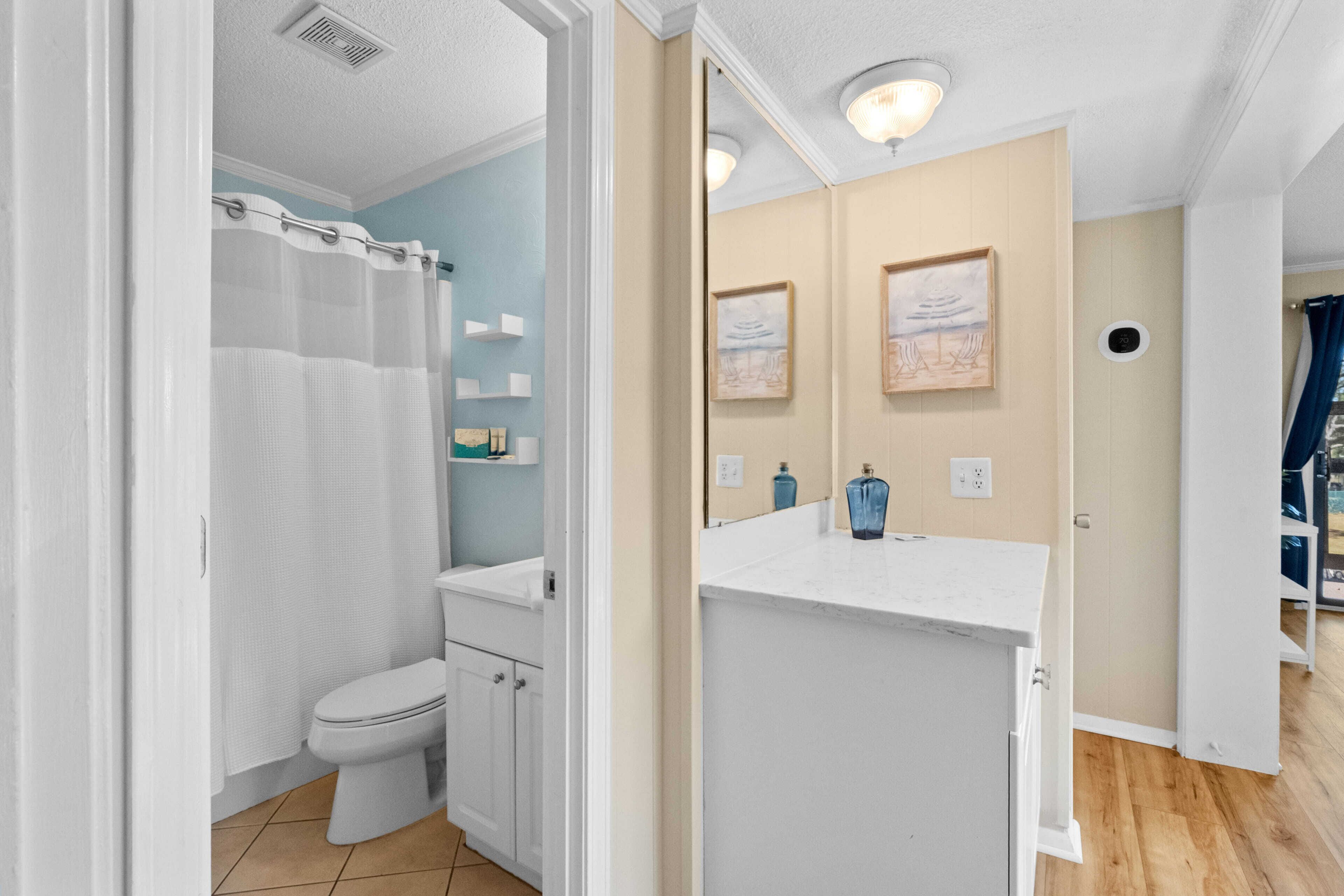 Un baño con inodoro, cortina de ducha y lavamanos con espejo.