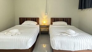 Habitación de hotel con dos camas individuales, una mesita de noche con lámpara y una lámpara de pared.