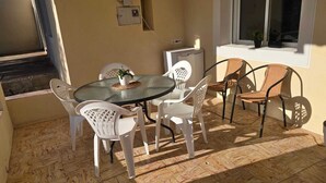 Eine Terrasse mit einem runden Tisch und Stühlen, einem kleinen Blumentopf und einem Fenster mit Blick.