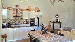 Eine moderne Küche mit weißen Schränken, einer Mikrowelle und einem Kühlschrank. Es gibt einen Esstisch mit Stühlen und eine dekorative Tischmitte.