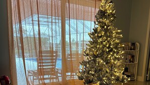 A living room with a Christmas tree, a large window with sheer curtains, and a bookshelf. - 3 Bedroom waterfront home w/access to ICW Bring your boat (Englewood)