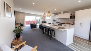 Una cocina moderna con una isla central, taburetes de bar y un área de comedor con sofá y mesa de centro.