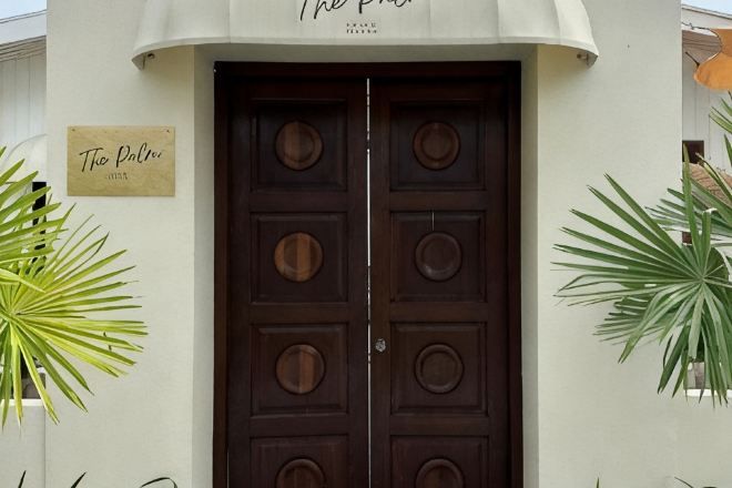 A double wooden door with a sign above it.