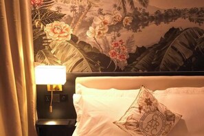 Een hotelkamer met een bed, een nachtkastje en een muurschildering.