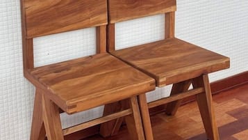 A wooden chair with a backrest and seat, positioned against a textured wall.
