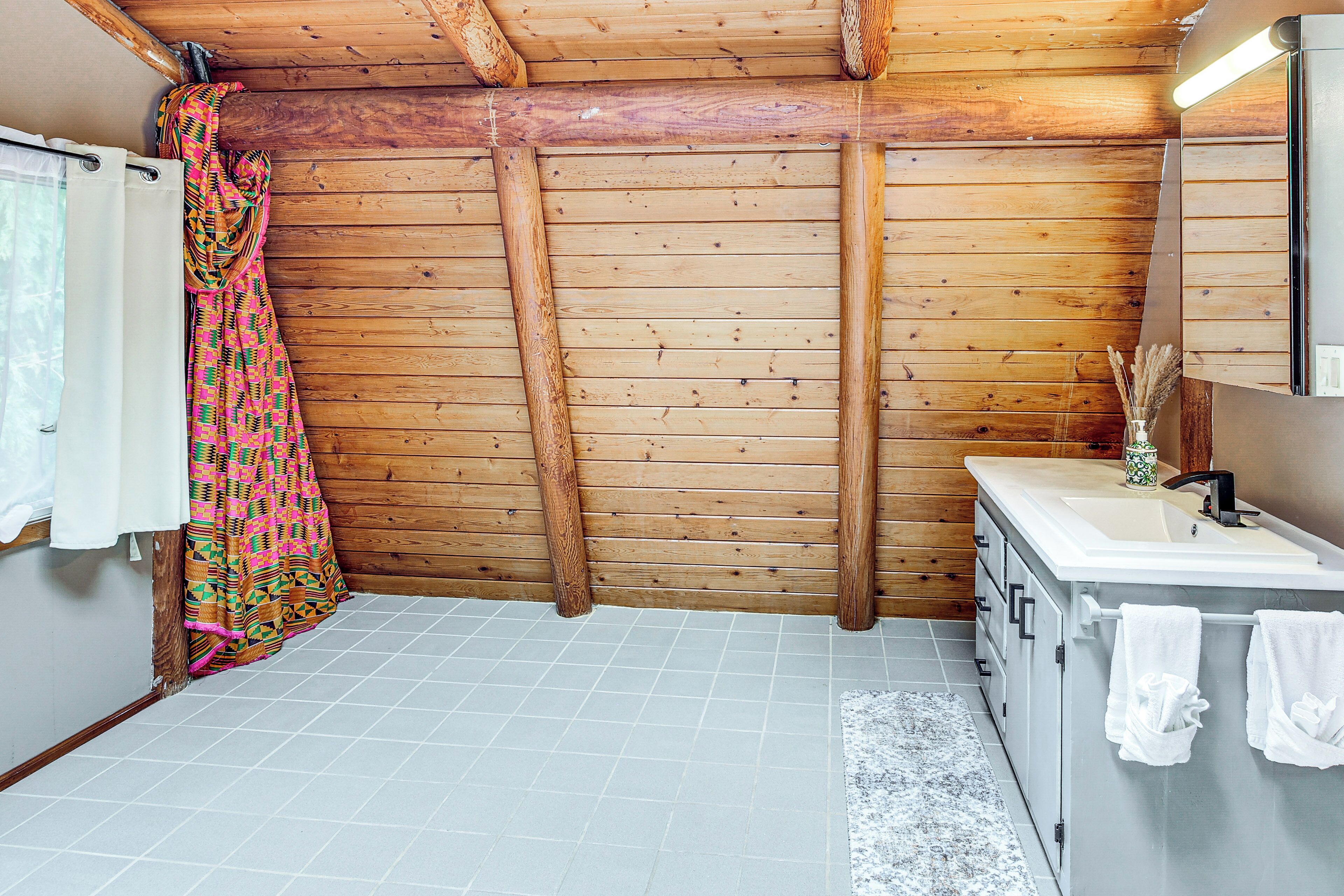 Ein Badezimmer mit Holzwänden, einem weißen Waschbecken und einem duschvorhang mit Muster.