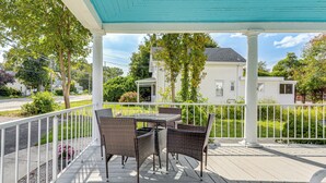 En overdækket terrasse med fletningsmøbler og gelænder i hvid.