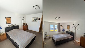 Un dormitorio con cama, mesita de noche, silla, perchero y ventana con cortinas.