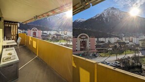 Un balcón con barandilla amarilla que da a una vista de un pueblo y montañas.