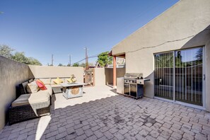 A patio with a grill, outdoor furniture, and a sliding glass door.