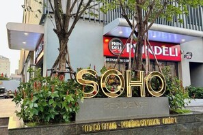 Een hotelschild met de naam 'SOHO RESIDENCE' en een grote boom ervoor.