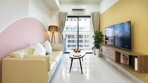 A modern living room with a sofa, a coffee table, a TV, and a balcony with curtains.