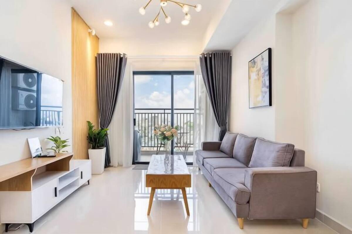 Un salon moderne avec un canapé, une table basse, un téléviseur et une vue sur le balcon.