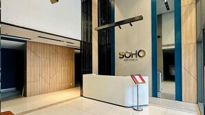 A reception area with a modern design, featuring a reception desk, a sign, and a wooden panel wall.