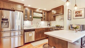 A modern kitchen with stainless steel appliances, wooden cabinets, and a central island. - Burlington Escape By Lake Champlain & Bike Path (Burlington)