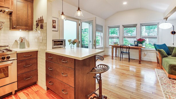 A kitchen with wooden cabinets, a central island, and a dining area with a table and chairs. - Burlington Escape By Lake Champlain & Bike Path (Burlington)
