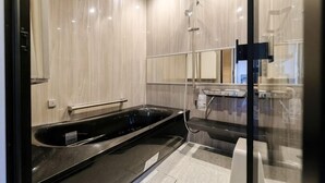 A modern bathroom with a large bathtub, a shower, and a glass-enclosed shower area. - Fandina E Resort (Kamakura)