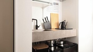 A kitchen with a countertop, a coffee maker, a knife block, and a cutting board. - Fandina E Resort (Kamakura)