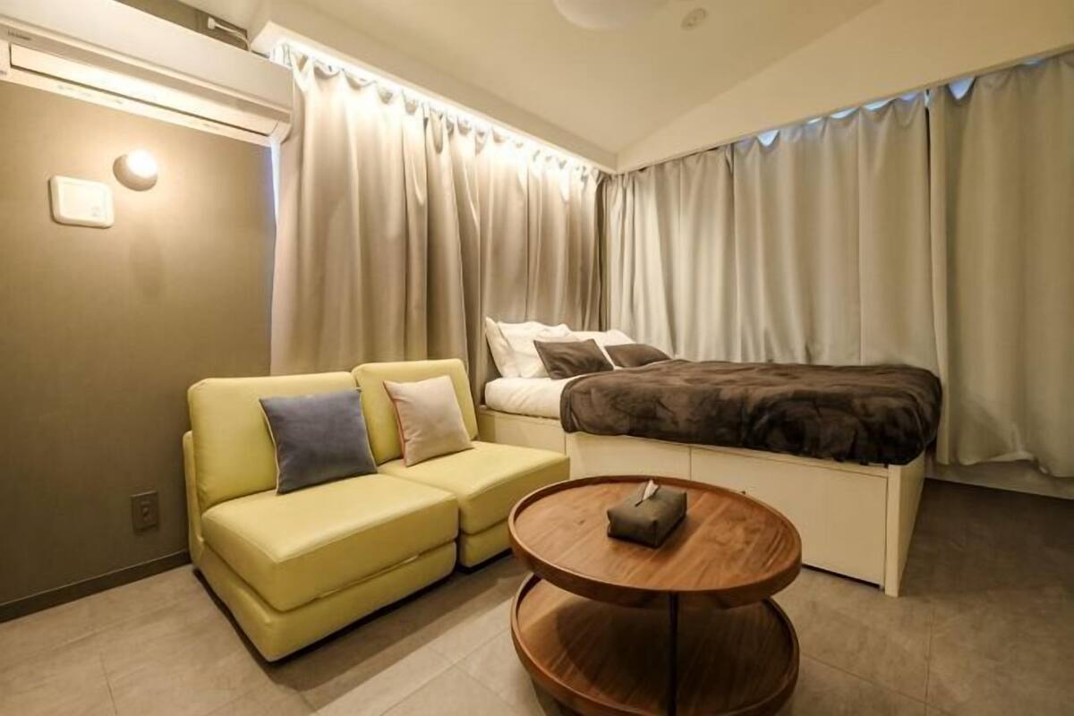 Ein Hotelzimmer mit Bett, Sofa, kleinem Tisch und Vorhängen.