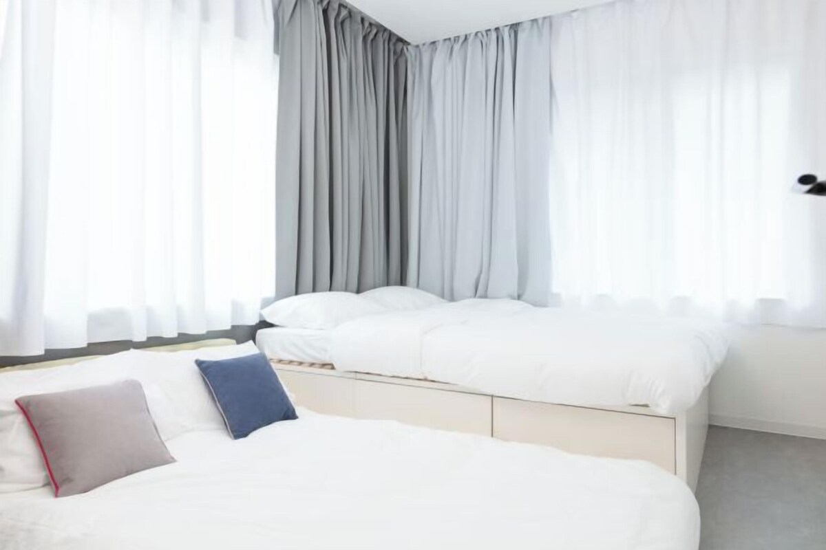 A modern bedroom with a bed, pillows, and curtains.