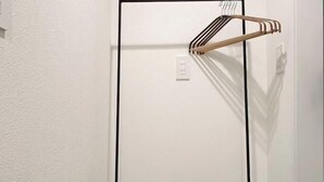 A white door with a black frame, a wooden hanger, and a power outlet. - Fandina E Resort (Kamakura)