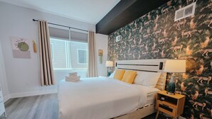 A modern hotel room with a large bed, wooden headboard, and a wall with a leopard print wallpaper.