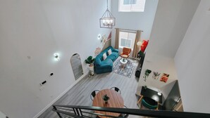A spacious living area with a blue sofa, a wooden coffee table, and a staircase leading to an upper floor.