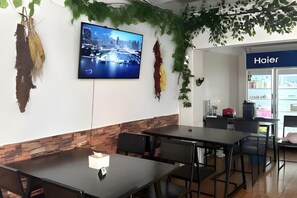 A conference room with a flat-screen TV, a brick accent wall, and a 'Hoier' sign in the background. - JC Home Stay (Bangkok)