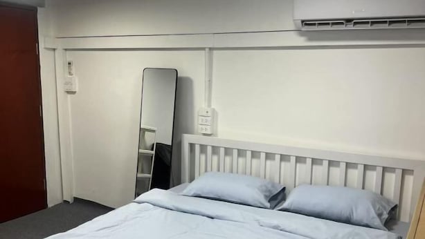 Une chambre d’hôtel avec un lit, un miroir et un appareil de climatisation.
