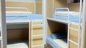 A bunk bed room with a wooden floor, white metal railings, and blue bedding. - JC Home Stay (Bangkok)