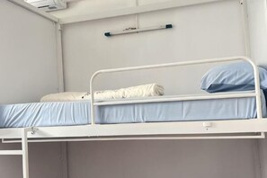 A bunk bed with a blue mattress and pillow, a white headboard, and a small shelf above. - JC Home Stay (Bangkok)