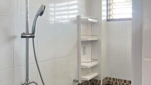 Un espace douche équipé d’un pommeau de douche à main et d’une étagère fixée au mur.